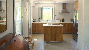 A modern kitchen with wooden cabinets, a central island, a refrigerator, and a window providing natural light. - Luxury Provencal Farmhouse with aircon, Pool, WiFI  -  Vaison/Malaucene area. (Malaucène)