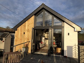 A modern house with a wooden exterior and large glass windows. - Self Catering Rural Cottage in Carmarthenshire (Peniel, Carmarthen)