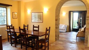 A dining area with a wooden table and chairs, a framed picture on the wall, and an archway leading to another room.