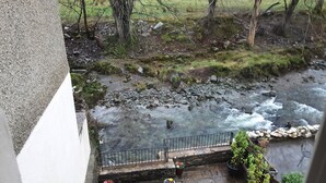 Een balkon met uitzicht op een rivier, buiten meubilair en bloempotten.