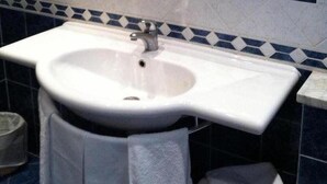 A bathroom with a white sink, a mirror above it, and a shower area. - Hotel il Cigno (Perugia)