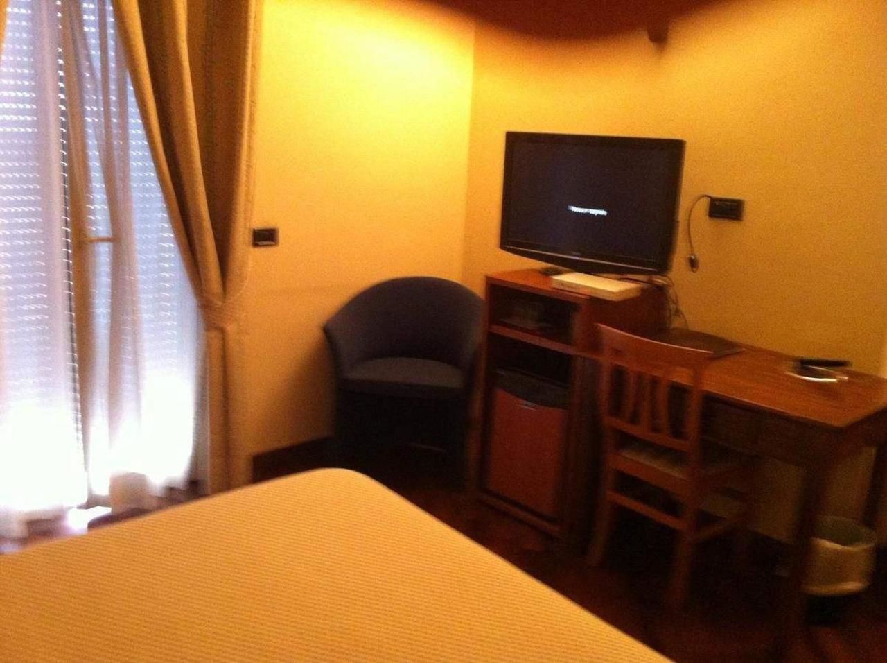 A hotel room with a bed, a desk, a chair, and a television.