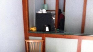 A small dining area with a table covered by a blue and yellow tablecloth, a wooden chair, and a black cabinet in the background. - Hotel il Cigno (Perugia)