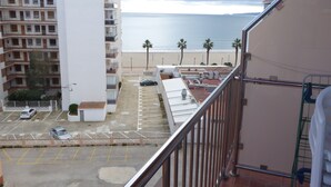 A view of a parking lot with a building in the foreground and a beach in the background. - FIRST LINE SEA APARTMENT (Rosas)