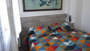 A bedroom with a bed, a painting on the wall, and a small statue on a nightstand. - FIRST LINE SEA APARTMENT (Rosas)