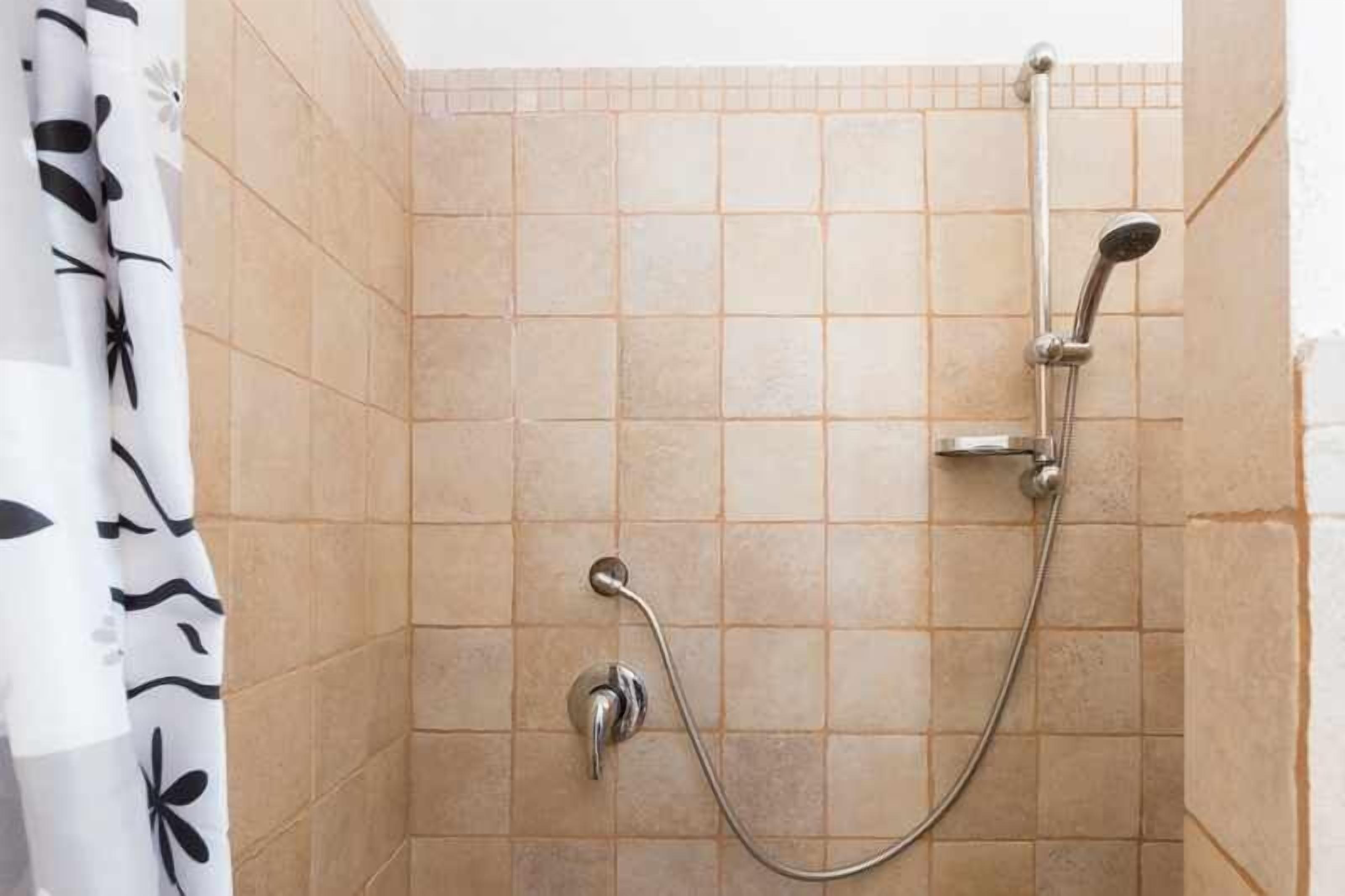 A shower area with tiled walls and a showerhead.