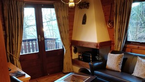 Un intérieur de chalet chaleureux avec une cheminée, des meubles en bois et de grandes fenêtres.