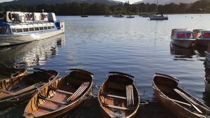 Une jetée au bord du lac, avec plusieurs petits bateaux en bois et un plus grand bateau à la coque bleue et blanche.