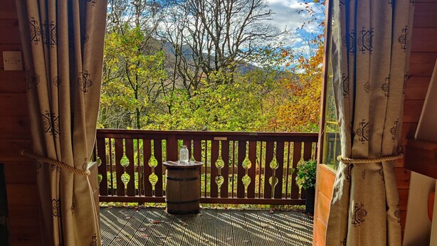Une terrasse en bois offrant une vue sur les arbres et les montagnes.