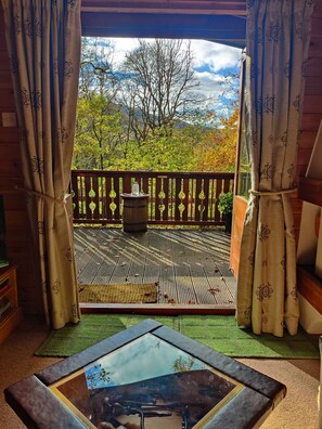 Una terraza de madera con vistas a árboles y montañas.