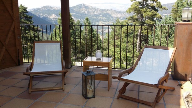Ein Balkon mit zwei Holzstühlen, einem kleinen Tisch und einer Laterne.