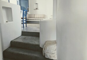 Eine Treppe führt zu einem Wohnbereich mit einem gestreiften Sofa und einem blauen Sessel.