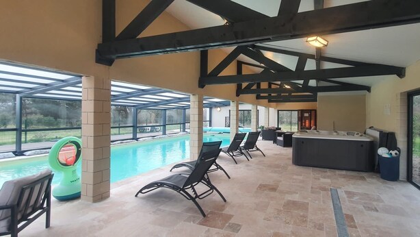 A covered outdoor area with a pool, lounge chairs, and a hot tub. - Domaine de La Retardière ****, heated swimming pool (Sepmes)