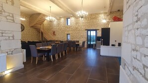 A spacious dining area with a stone wall backdrop, a staircase, and a modern chandelier. - Domaine de La Retardière ****, heated swimming pool (Sepmes)