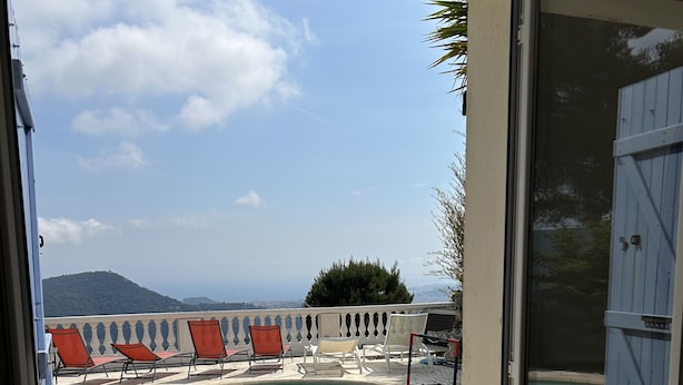 A pool area with lounge chairs and a view of a mountainous landscape.