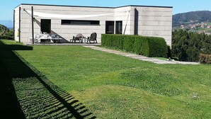 Un bâtiment moderne doté d’un toit plat, d’une grande fenêtre et d’un patio aménagé avec du mobilier d’extérieur.