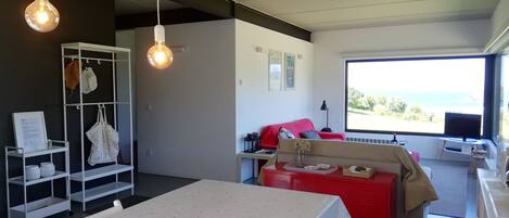 Un salón moderno con una mesa de comedor, un sofá rojo y un ventanal que ofrece vistas al exterior.
