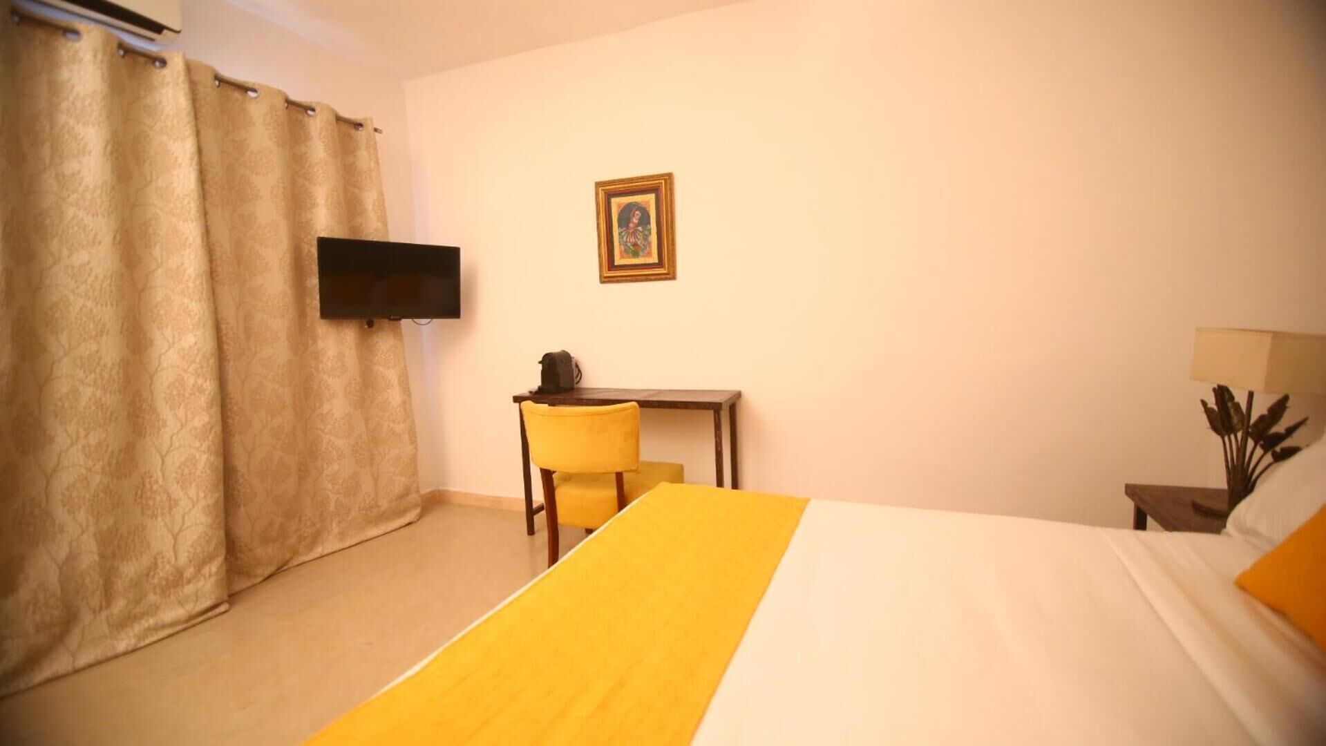 A hotel room with a bed, a desk, a chair, a television, and a picture on the wall.