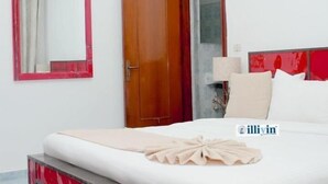 Ein Hotelzimmer mit einem Bett, einer Holztür, einem Spiegel und einer roten Akzentwand.