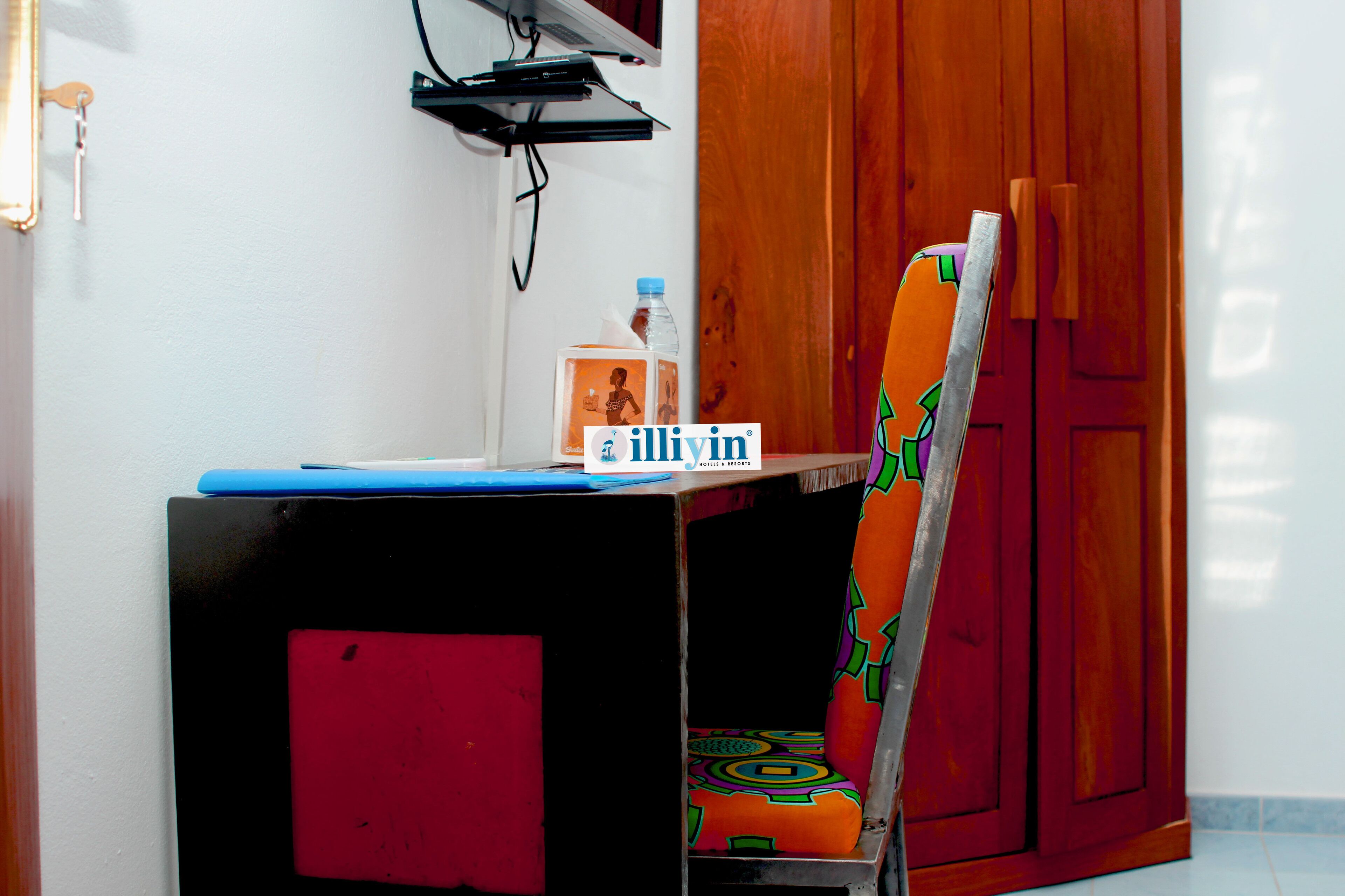 A small desk with a laptop, a bottle, and a tissue box.