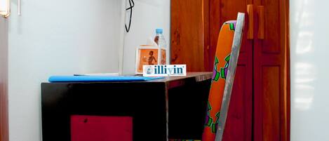 A small desk with a laptop, a bottle, and a tissue box.