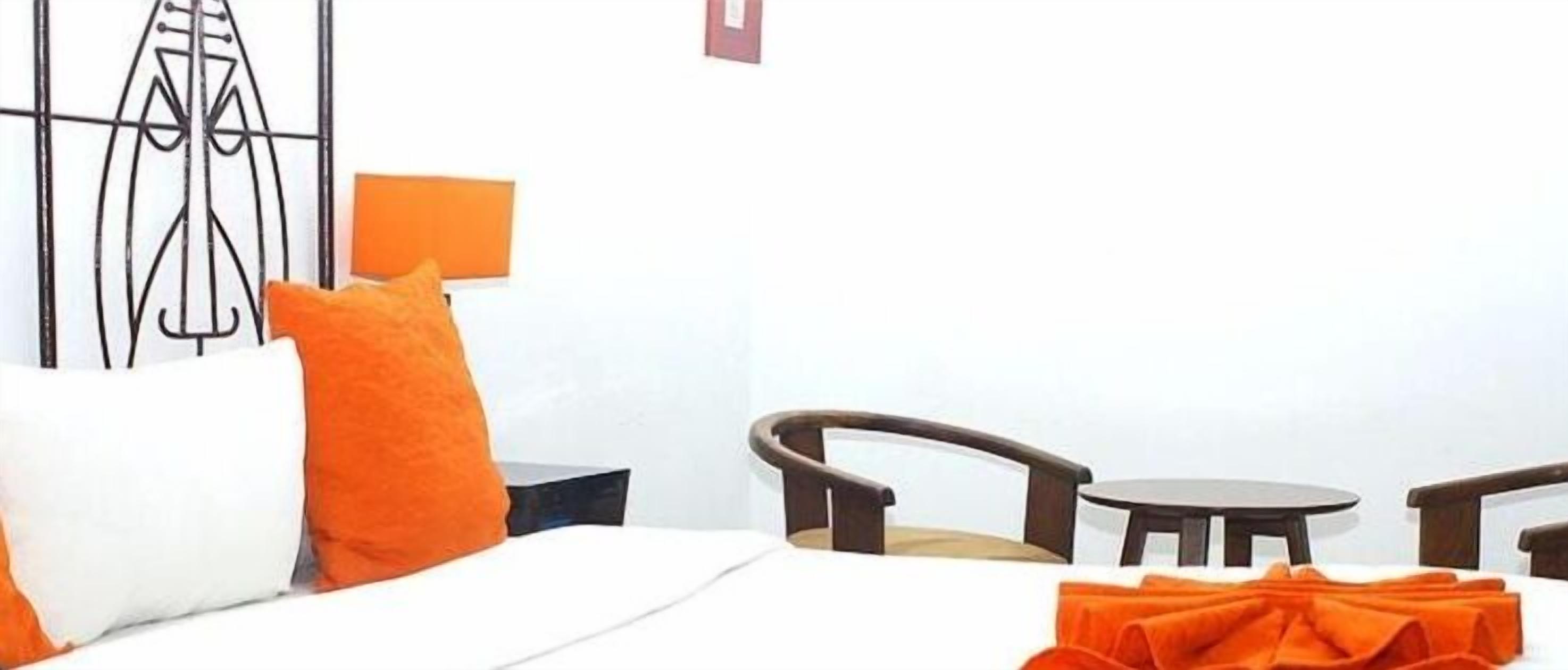 Una habitación de hotel con cama, una silla, una mesita y una obra de arte en la pared.