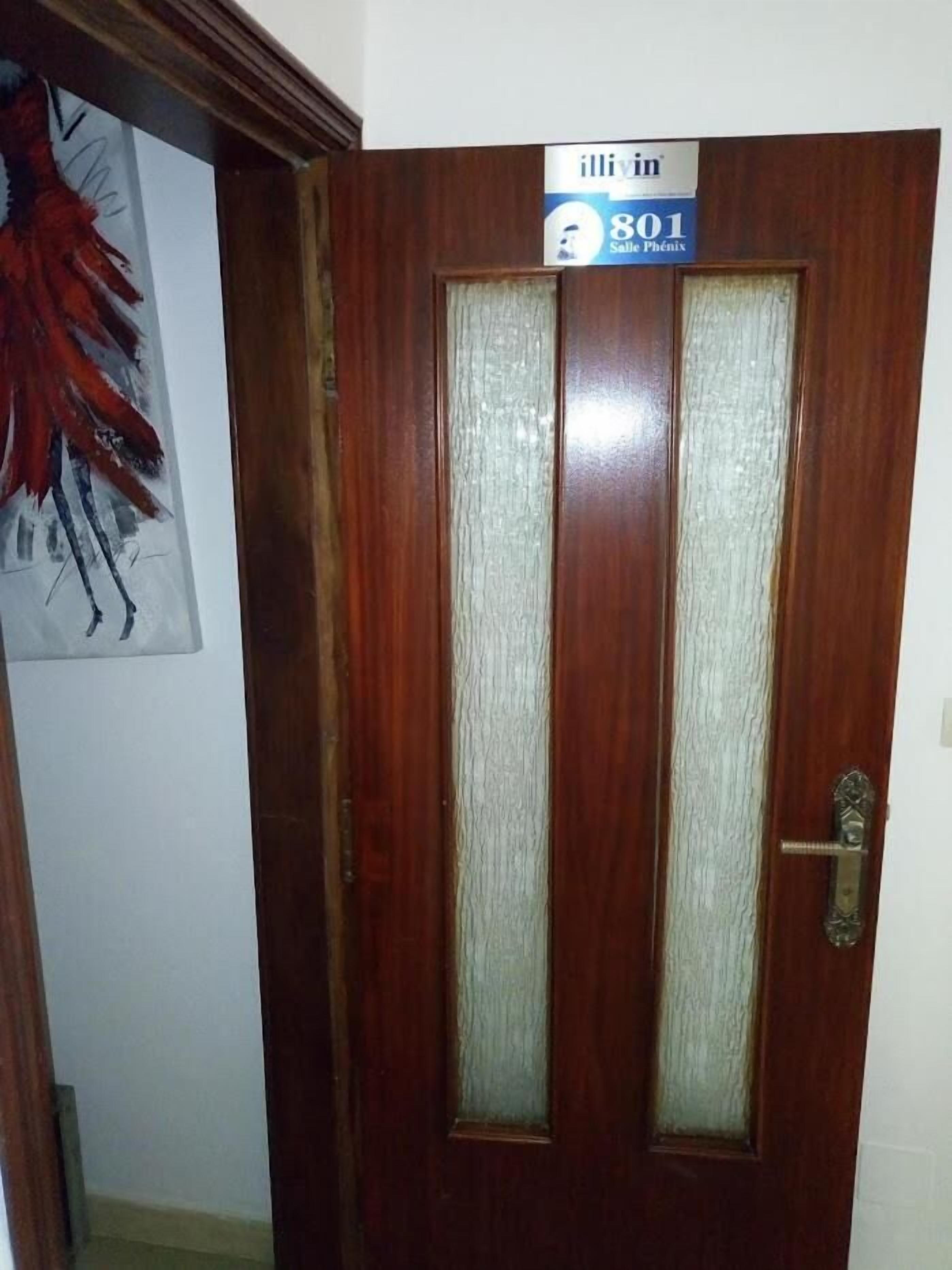 A wooden door with a frosted glass panel and a sign above it.