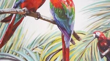 Two colorful parrots perched on a branch with tropical foliage in the background.