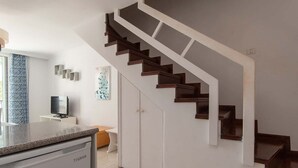 Una cocina moderna con lavavajillas integrado, una escalera de madera y un armario blanco.