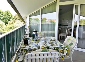 Een balkon met een tafel gedekt voor twee personen, een waterkoker en een kleine plant in een pot.