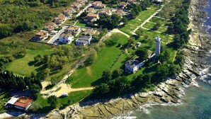 An aerial view of a coastal residential area with houses, a lighthouse, and a rocky shoreline. - Apartment Eva in Zambratija-Savudrija, air-conditioned, close to the beach (Umag/ Zambratija)