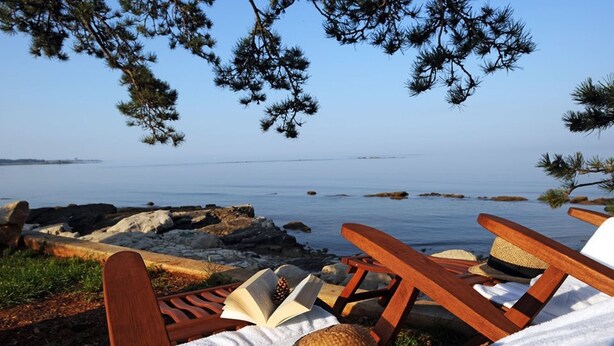 A beachside lounge with wooden chairs and straw hats, overlooking a calm sea and rocky shoreline. - Apartment Eva in Zambratija-Savudrija, air-conditioned, close to the beach (Umag/ Zambratija)
