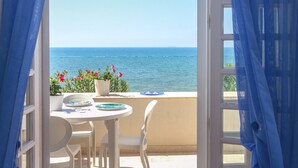 Un balcon ouvert avec une table et des chaises, donnant sur la mer.