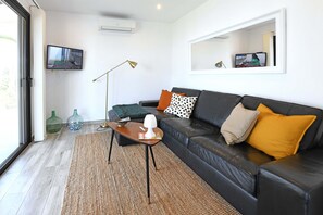 A modern living room with a leather sofa, a coffee table, and a television mounted on the wall.
