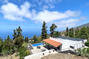 Eine moderne Villa mit Schwimmbad, Sitzgelegenheiten im Freien und Meerblick.