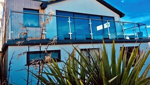 Een modern huis met twee verdiepingen, grote ramen en een balkon.