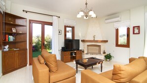 A living room with a fireplace, a television, and a bookshelf. - Villa Evanthia,a Place To Be! (Rethymno)