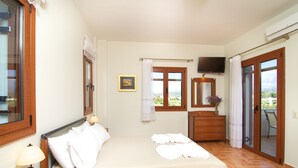 A bedroom with a bed, a dresser, a TV, and a window with a view. - Villa Evanthia,a Place To Be! (Rethymno)
