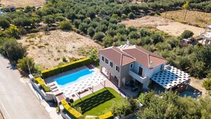 An aerial view of a residential property with a swimming pool, a well-maintained garden, and a large house with a tiled roof. - Villa Evanthia,a Place To Be! (Rethymno)
