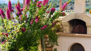 A stone building with a brick oven, surrounded by lush greenery and flowering plants. - Villa Evanthia,a Place To Be! (Rethymno)
