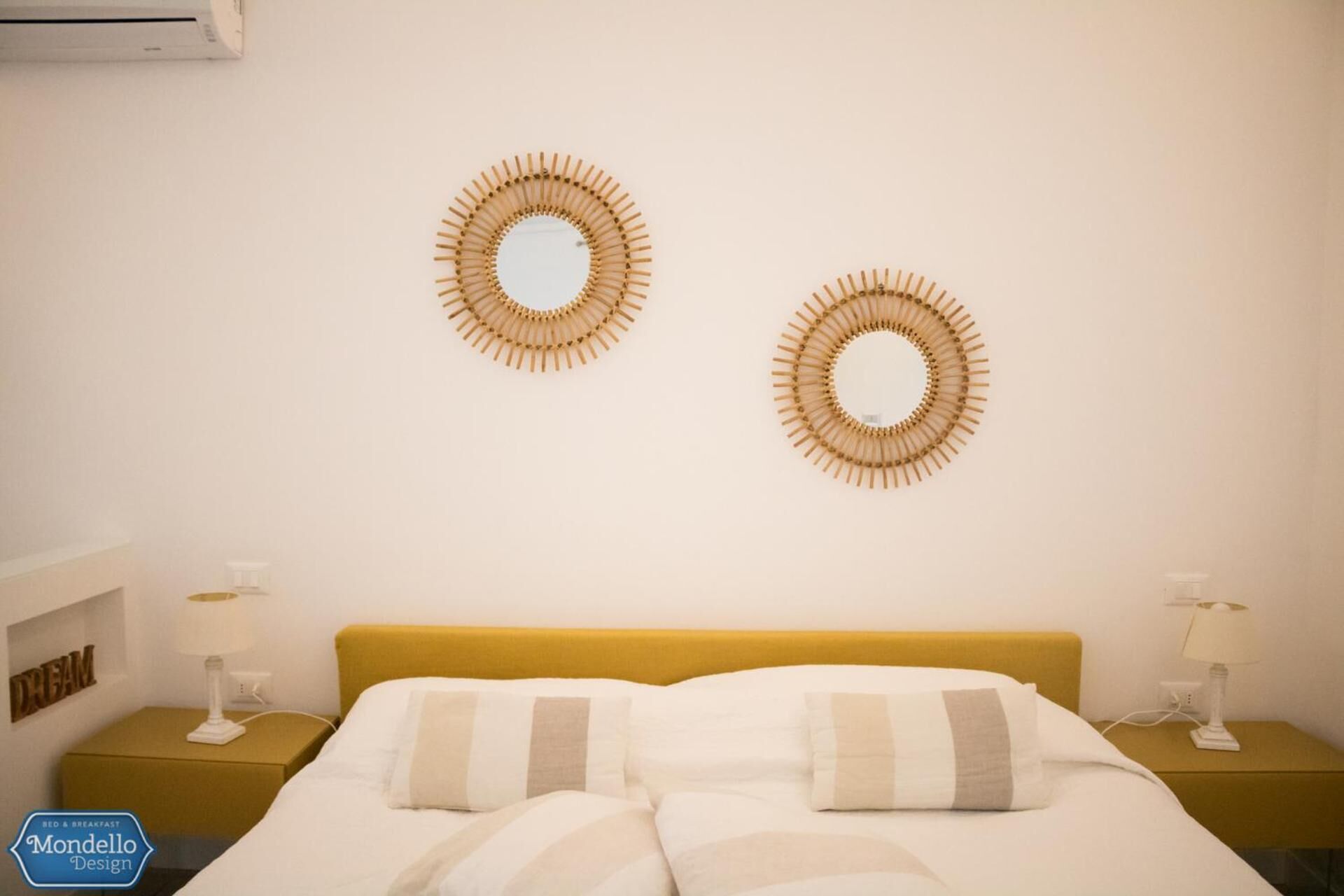 A hotel room with a bed, two bedside tables, and two wall-mounted mirrors.
