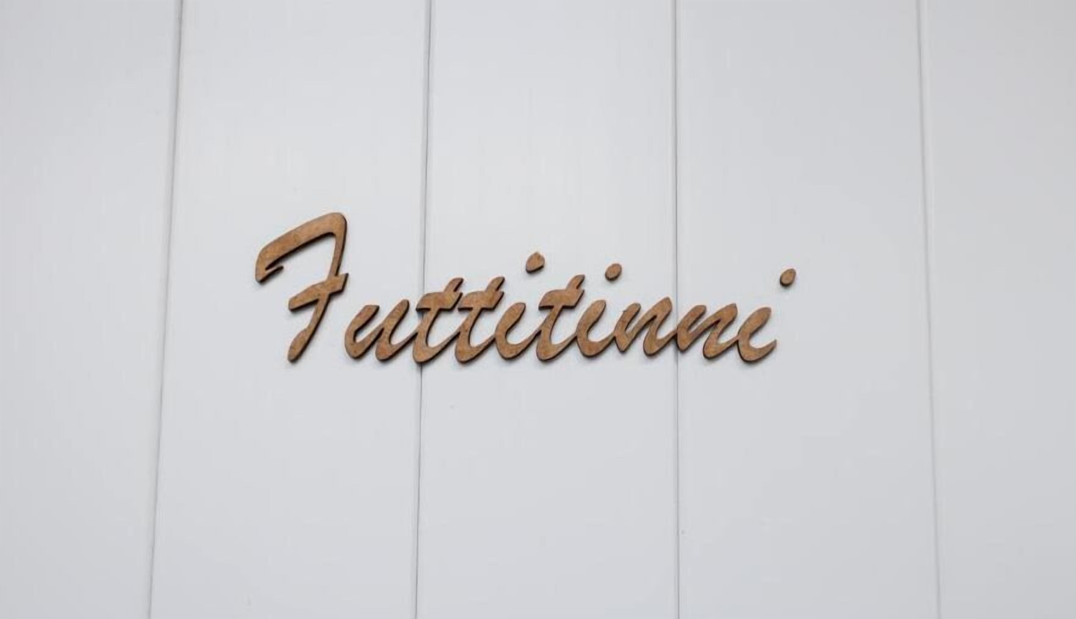 Un letrero de madera con la palabra 'Futtitinni' escrita en una caligrafía cursiva.