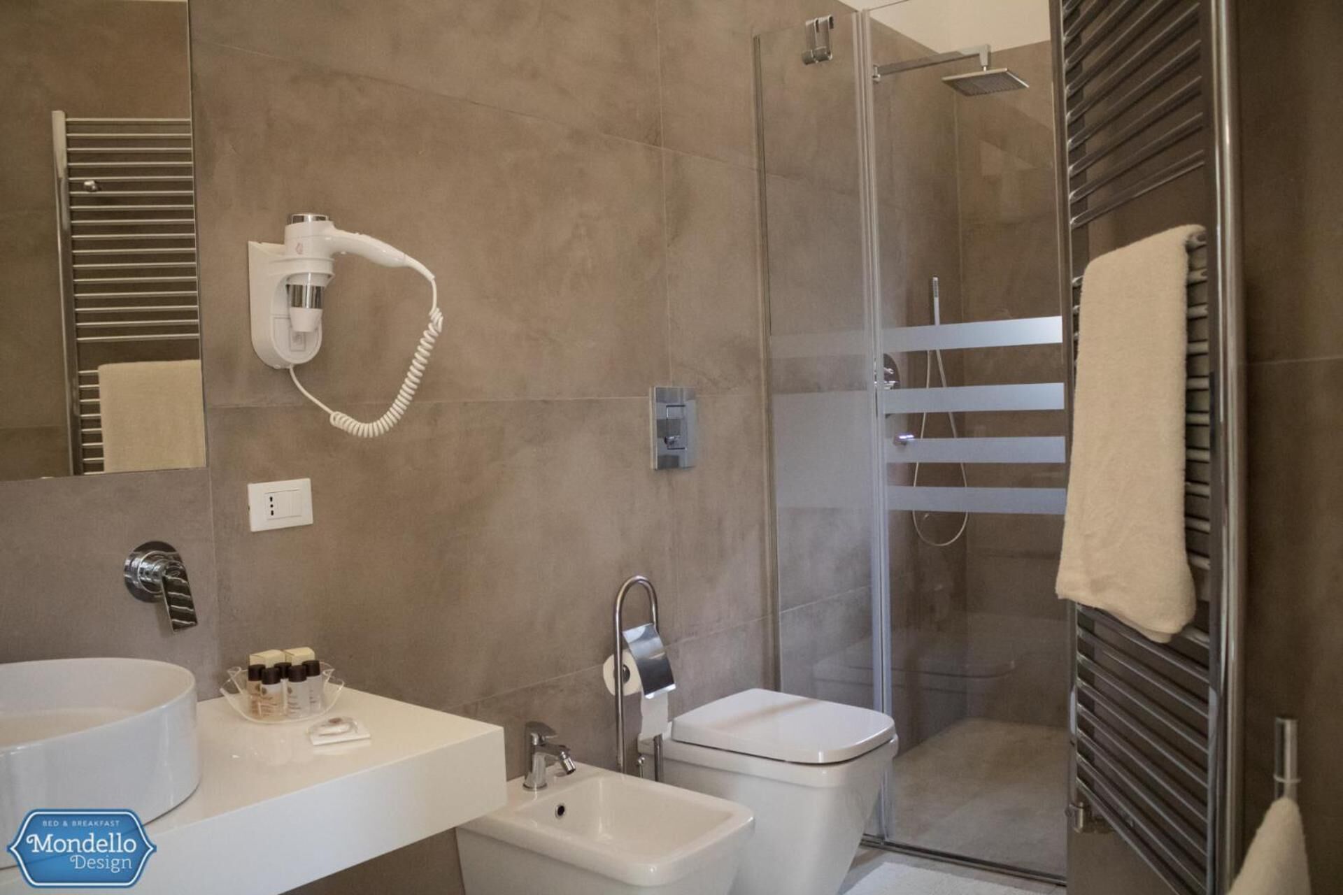 Ein modernes Badezimmer mit großem Spiegel, Waschbecken, Toilette und einer Duschkabine.