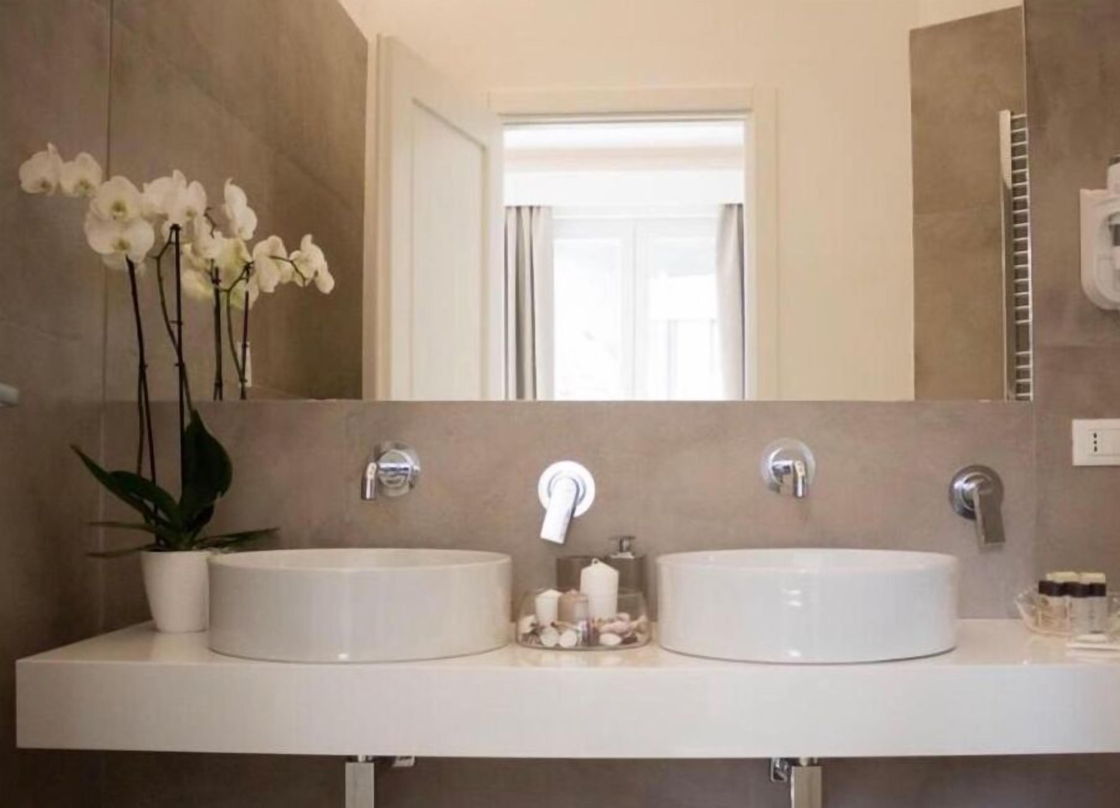 A bathroom with two sinks, a mirror, and a potted orchid.