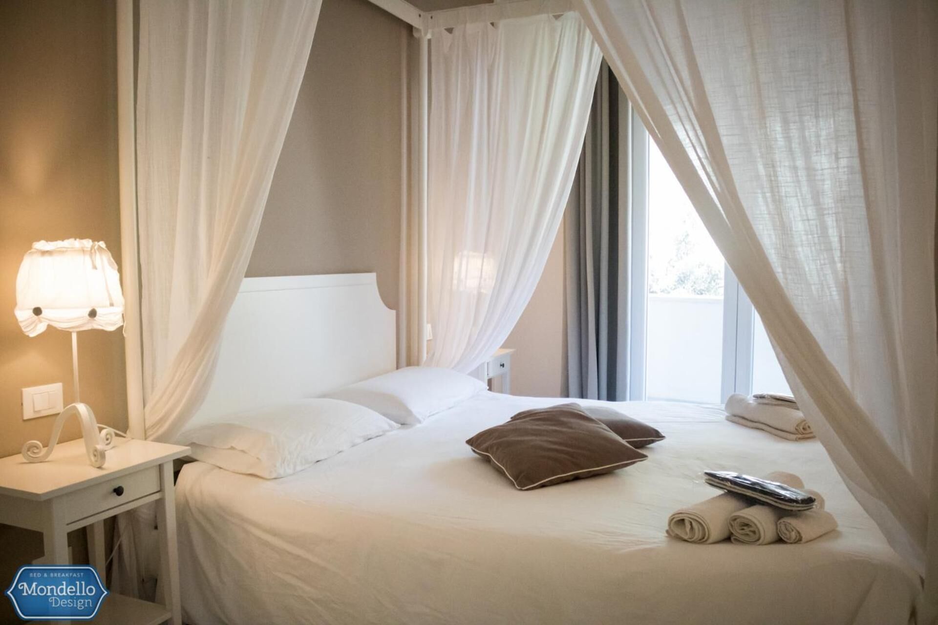 A neatly made bed with white linens, a brown pillow, and a remote control.