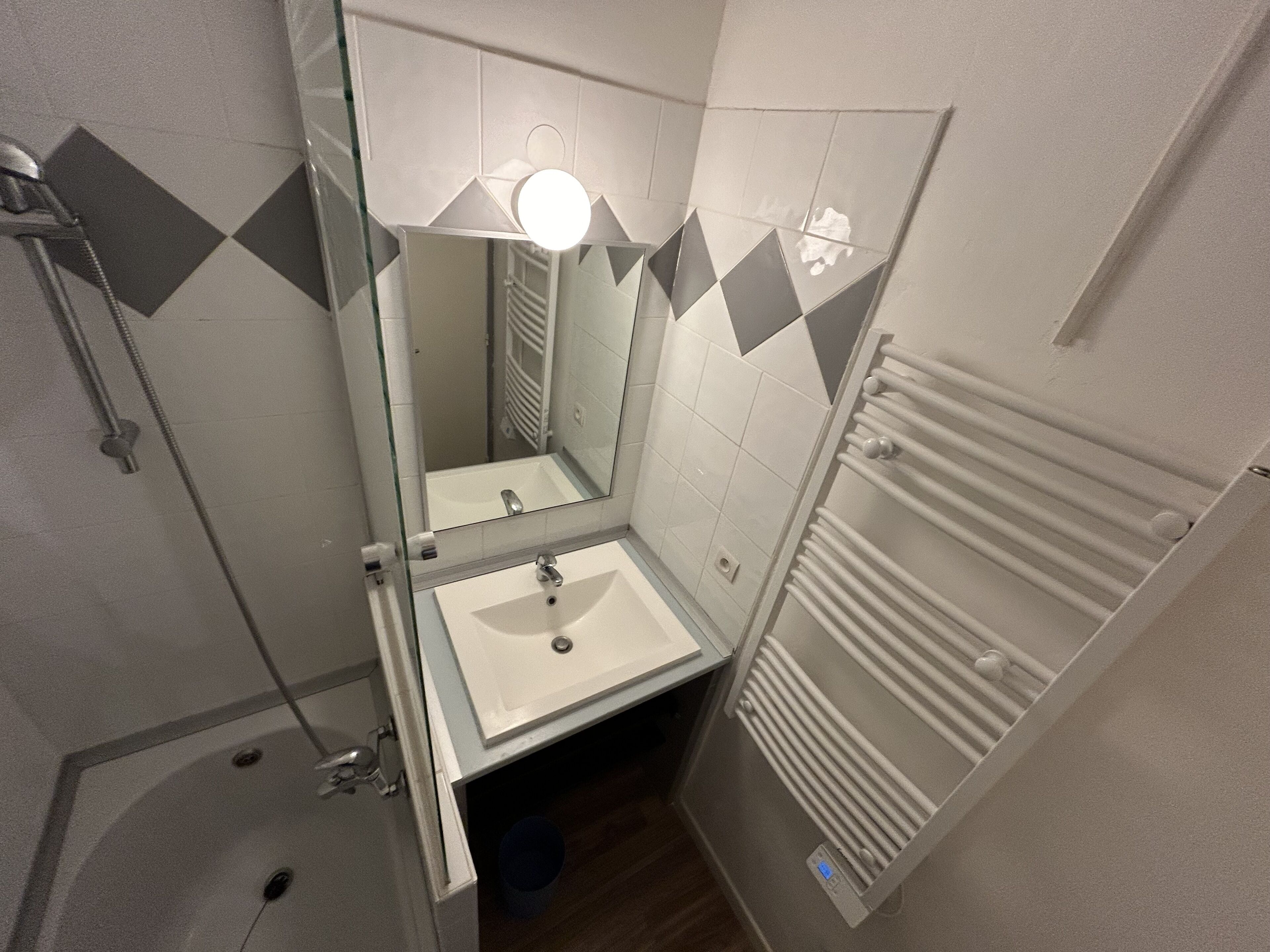 A compact bathroom with a shower, a sink, and a mirror.