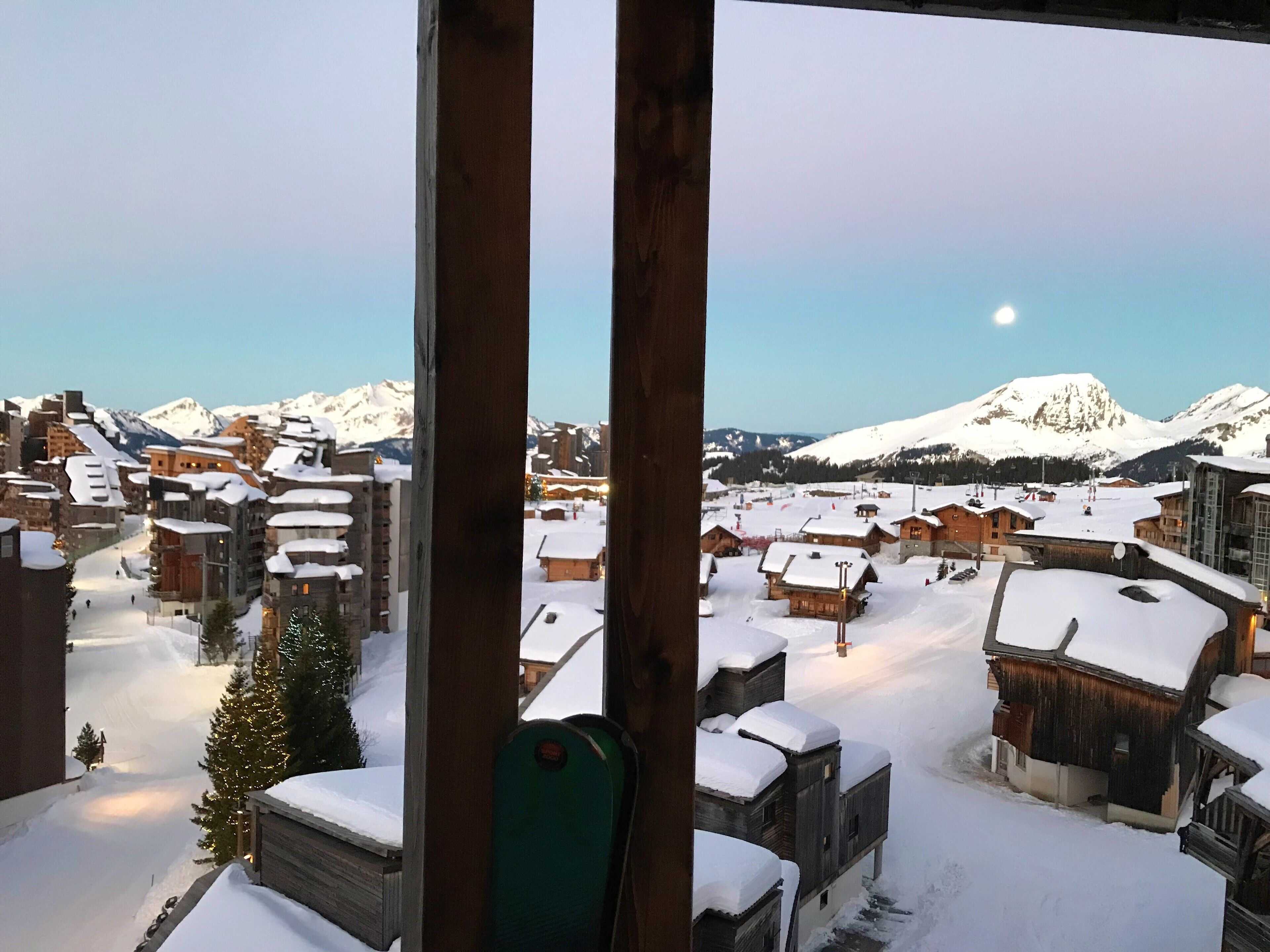 Un pueblo montañoso cubierto de nieve con edificios de madera y una pista de esquí.