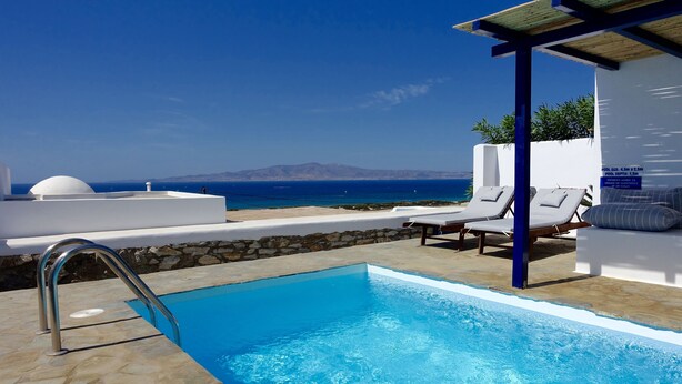 En pool med fri utsikt över havet, solstolar och en pergola.