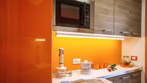 A modern kitchen with a built-in microwave, a coffee maker, and a kettle on the counter.