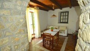 A dining area with a stone wall, wooden ceiling, and tiled floor.